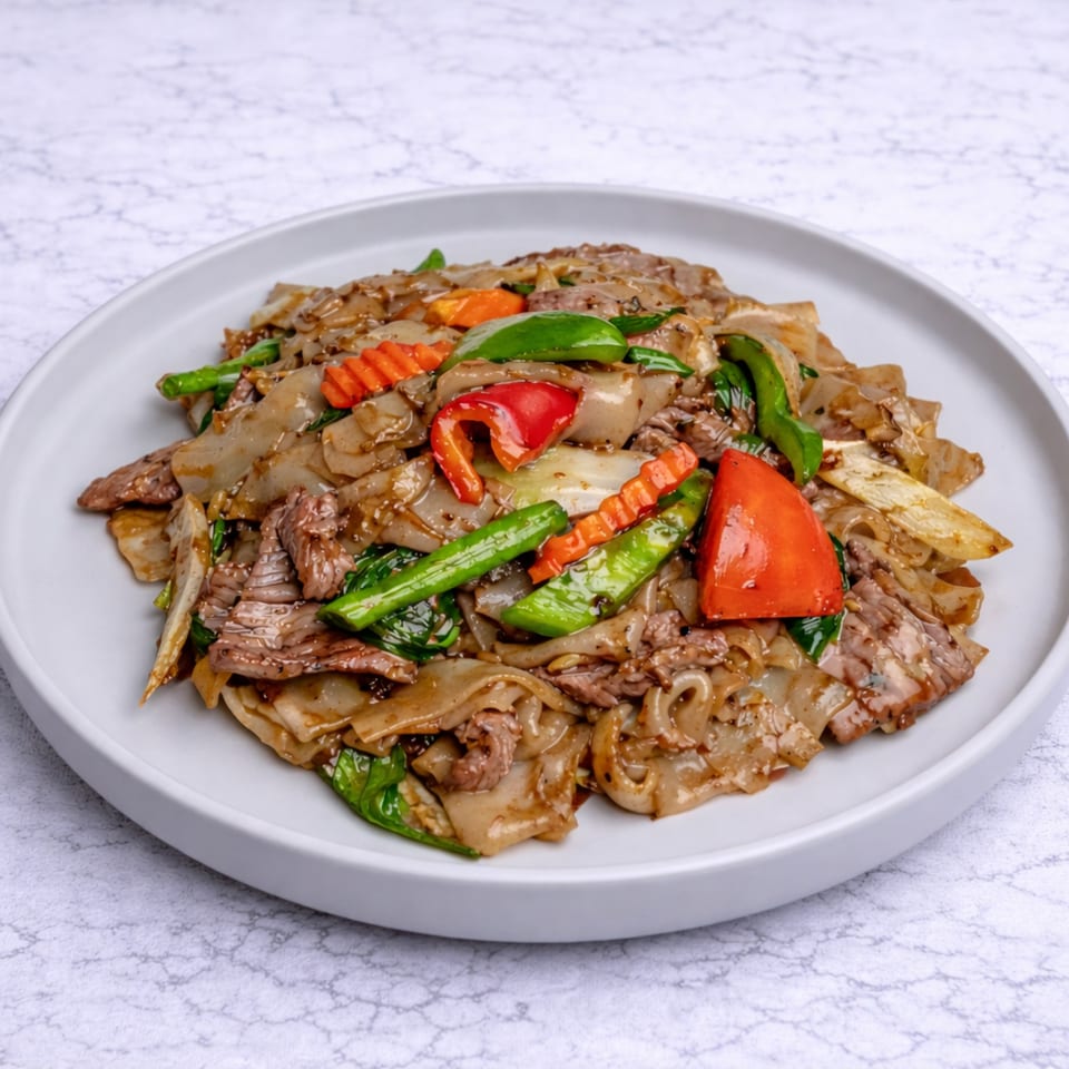 Linjee Thai's Pad See Ew with wide noodles, beef, and colorful vegetables on a white plate.
