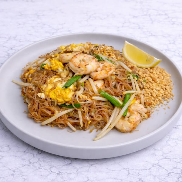 Linjee Thai's Pad Thai with shrimp, egg, bean sprouts, and peanuts, garnished with a lemon wedge.
